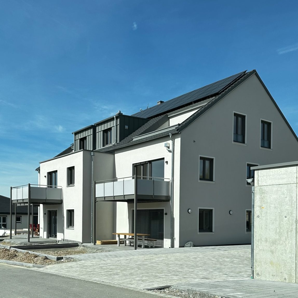Moderne Wohnhäuser mit Balkonen und klarer Architektur in ruhiger Umgebung.