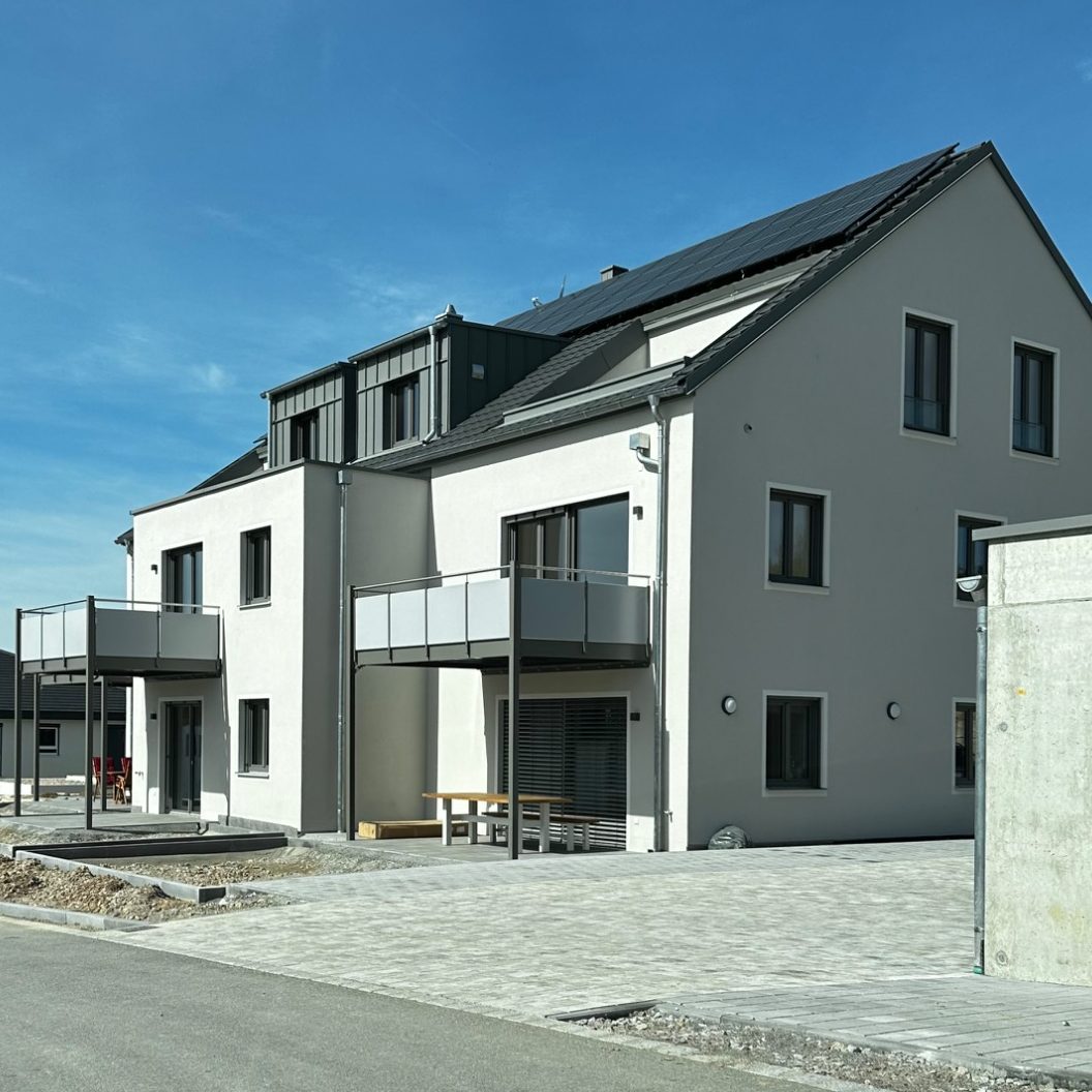 Moderne Wohngebäude mit Balkonen und asphaltierter Zufahrtsstraße.